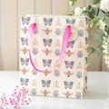 Medium gift bag with pink rope handles and colorful floral bug pattern