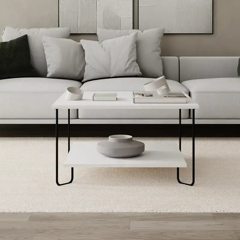 Modern coffee table with white top, black metal frame, and wide lower shelf.