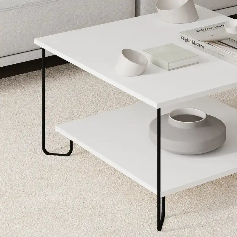 Modern two-tier coffee table with white top, black metal legs, and storage shelf