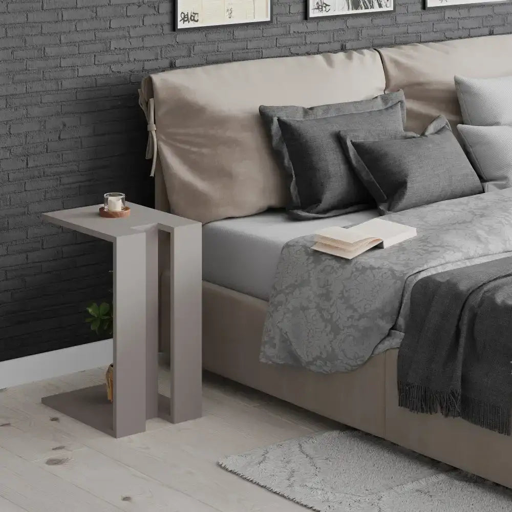 White C-shape side table with flat top and open sides next to a sofa