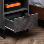Dark grey bedside table drawer open with internal shelf, steel legs.