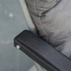 Grey cushion on dark frame with textured protective end cover on the armrest
