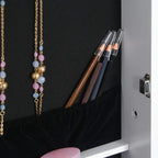 White jewelry cabinet shelf with necklaces and makeup brush holder near lock