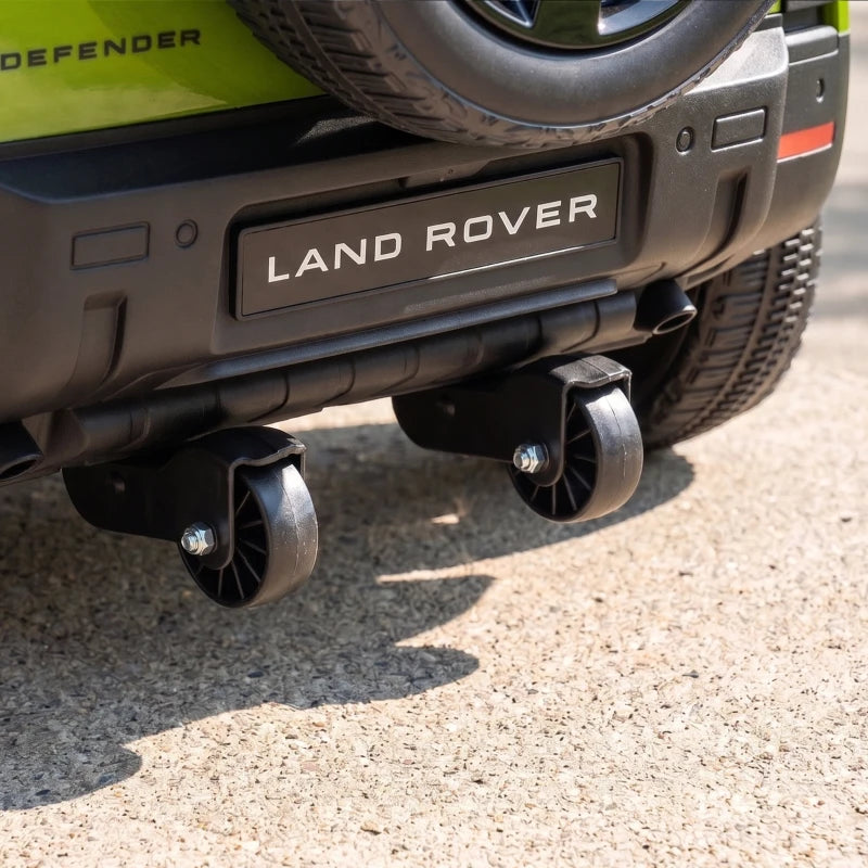 Lower rear view of green ride-on car showing metal footrests and rear exhaust-style details