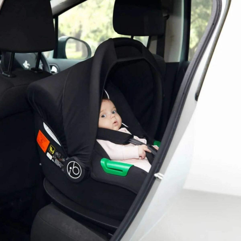 Black i-Size infant car seat installed in car, side view with green release bars