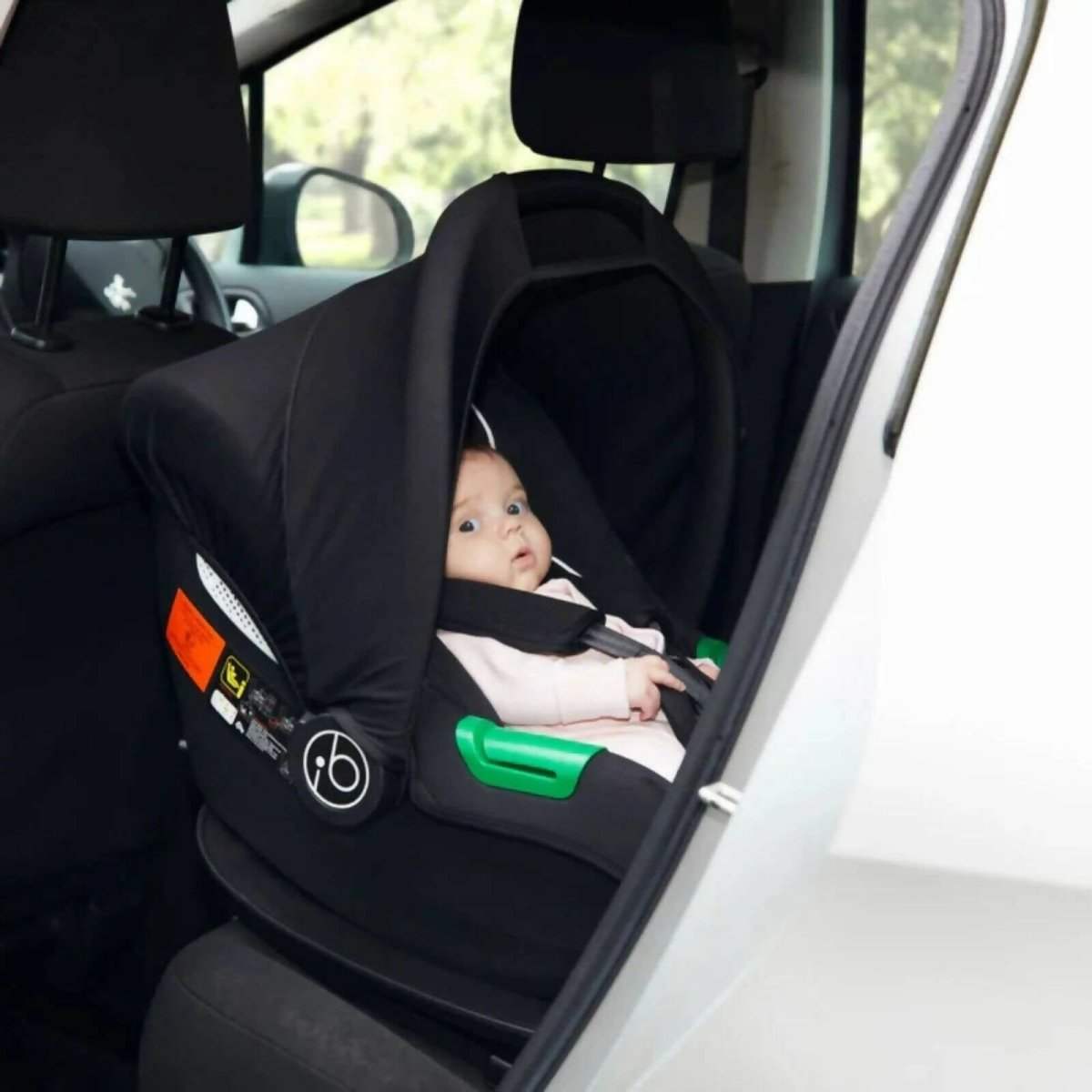 Black i-Size infant car seat installed in car, side view with green release bars