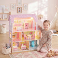 Pink 3-level dollhouse with warm LED lighting, front railing, and furnished interior rooms.