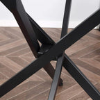 Close-up of black crossed metal legs under a round clear glass table top
