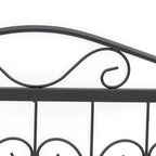 Close-up of black metal fence top rail with curling scroll ornament and posts