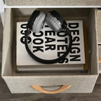Light grey fabric drawer chest with pull handle showing books and headphones inside