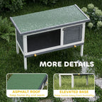Grey wooden rabbit hutch with asphalt-style roof and elevated base on white legs
