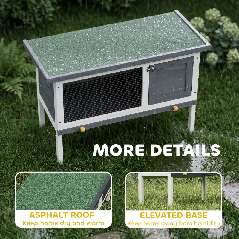 Grey wooden rabbit hutch with asphalt-style roof and elevated base on white legs