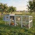 Grey wooden chicken coop with covered run, wire mesh walls, and hens foraging