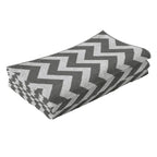 Folded reversible rug mat with light grey and white zigzag chevron pattern