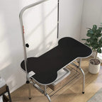 Pet grooming table close-up with black tabletop, curved edges, and lower metal storage rack