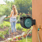 Wall-mounted garden hose reel spraying with extended hose and teal nozzle