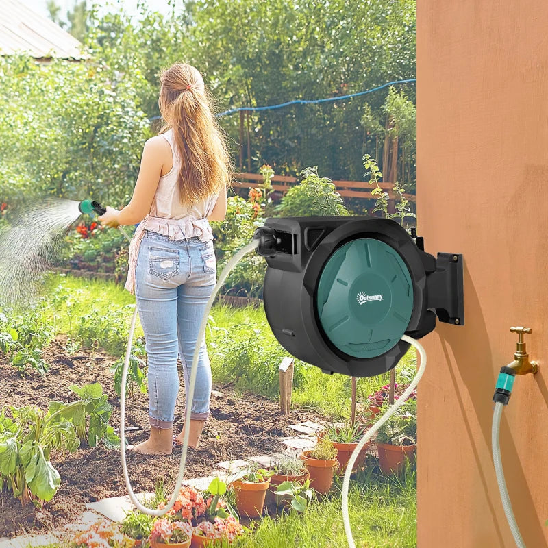 Wall-mounted garden hose reel spraying with extended hose and teal nozzle