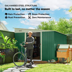 Green metal storage shed with wide double sliding door open for outdoor items