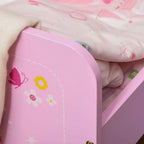 Close-up of pink end panel with castle graphic and safety rail, with patterned bedding nearby