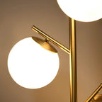Gold three-light floor lamp with round white globe shades and gold metal arms