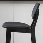 Black bar stool featuring a thick padded backrest and cushioned faux-leather seat