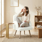 Cream velvet armchair with curved arms, cushioned seat, and wooden legs