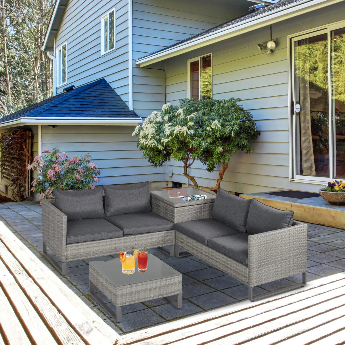 Grey rattan garden sofa set with cushions and two tables arranged outdoors