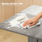 Grey wood-effect tabletop being wiped clean with a cloth.