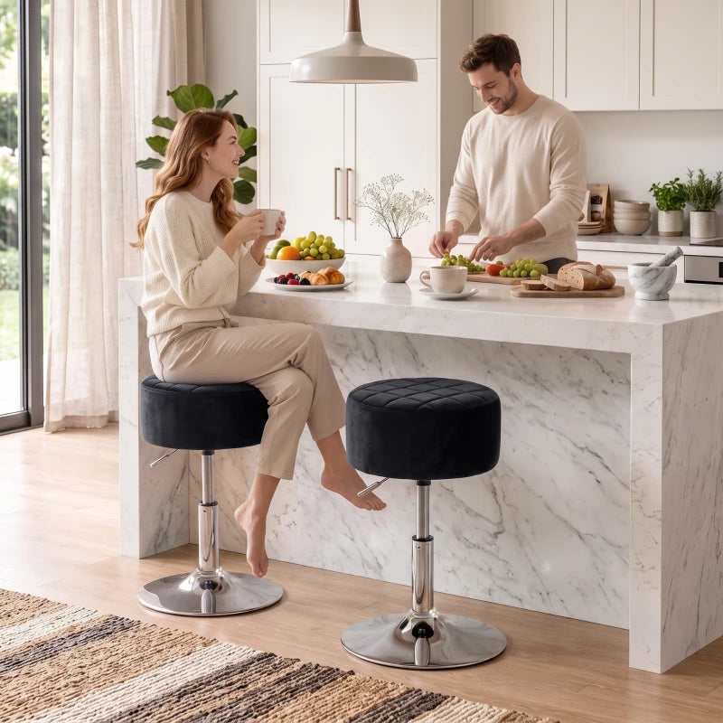 Two black swivel bar stools with round padded seats and chrome bases