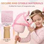 Pink plush unicorn stick horse with grip handle and gold horn, child holding