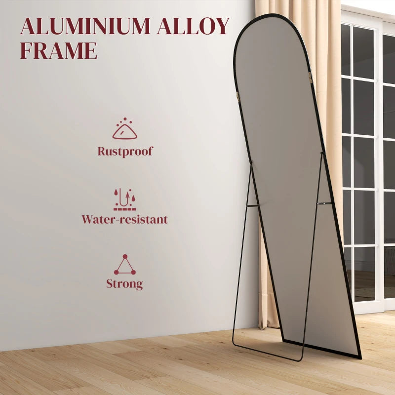 Black standing mirror with arched top and thin frame on narrow legs