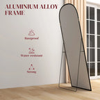 Black standing mirror with arched top and thin frame on narrow legs