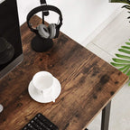 Brown wood desk top with black steel frame, with headphones, mug, and keyboard