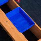 Blue plastic basin set inside a wooden kids sandbox divider compartment