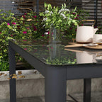 Grey aluminium table with tempered glass top, corner view with plants on it