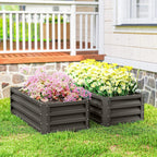 Two dark grey steel planter boxes with pink and yellow flowers in a backyard lawn