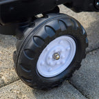 Large black plastic tire with white wheel hub on ride-on construction tractor