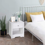 White nightstand with drawer and open shelf beside bed, styled with decor.