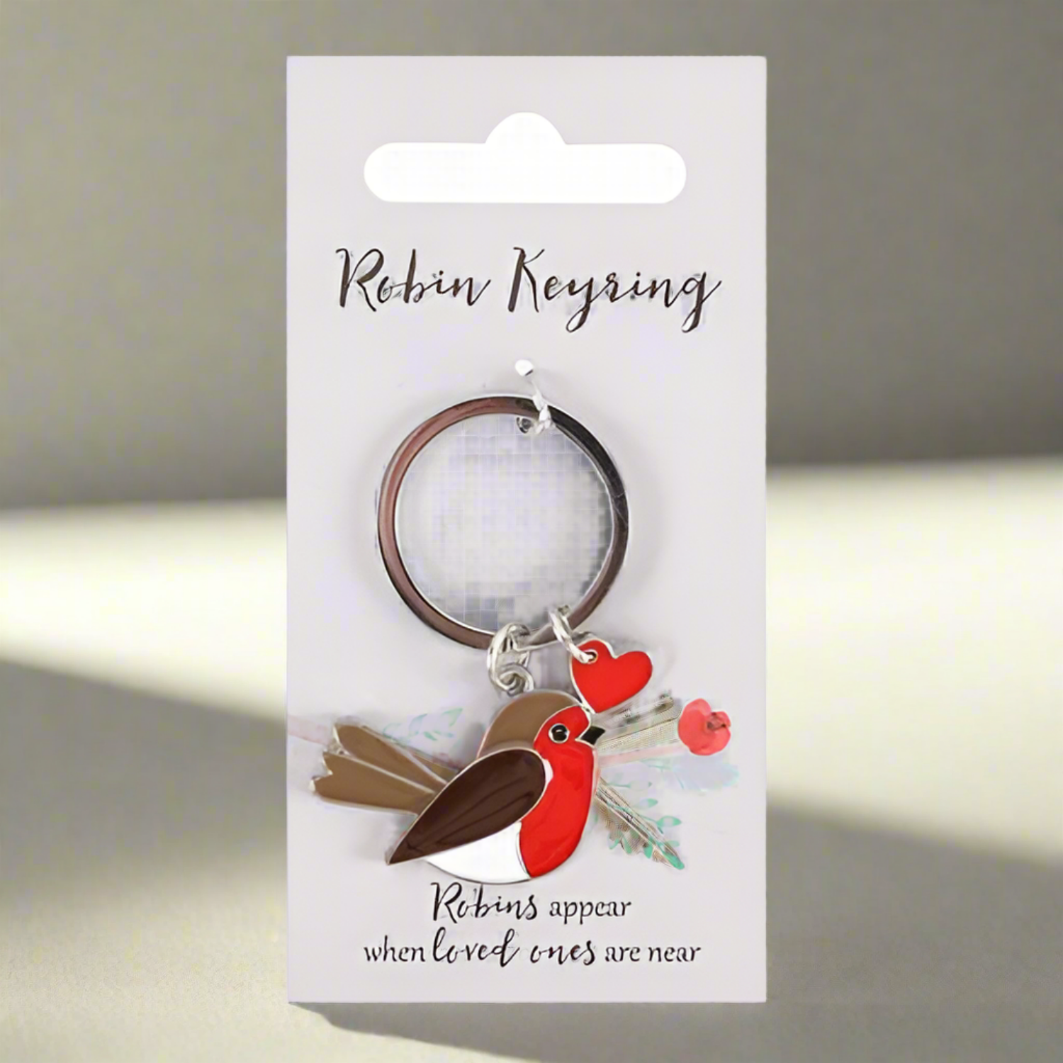Keychain with a red bird and heart charm on a wooden surface