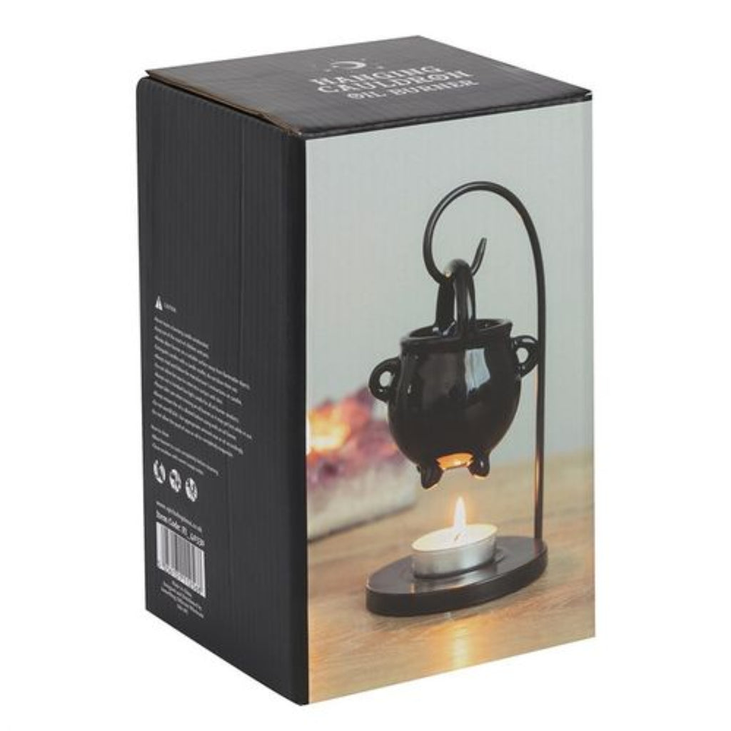 Black cauldron-shaped lamp with a candle on a product packaging box.