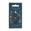 Gold keyring with hare design on a blue packaging card with floral illustrations