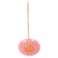 Pink circular sun incense holder with incense stick and smiling sun face design