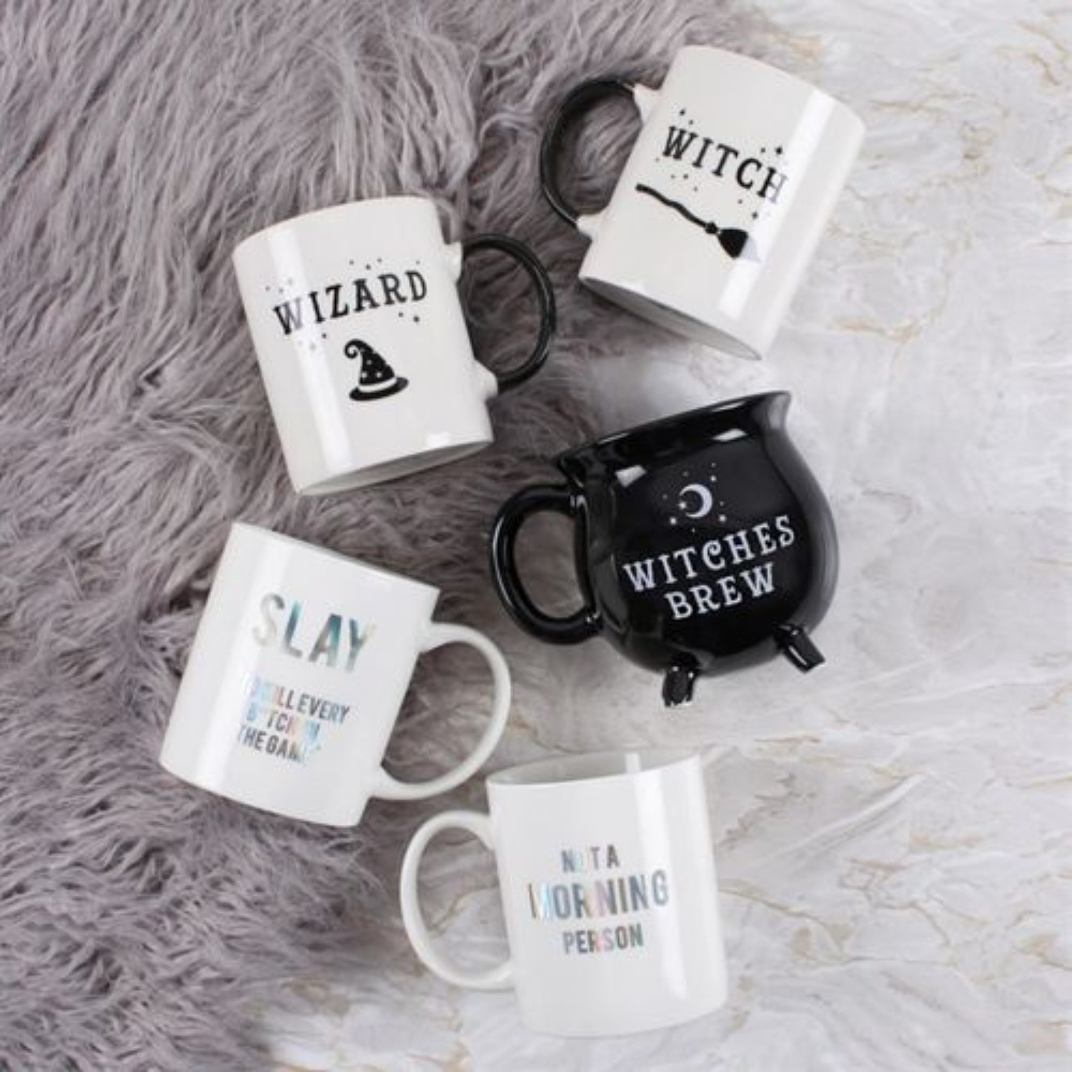 Set of mugs with Halloween-themed text and designs on a textured surface.