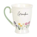 White pedestal mug with green handle, 'Grandma' script, and wildflower print
