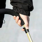 Hand adjusting and securing the handle latch on a black pet stroller.