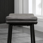Grey padded bar stool seat with stitched edge and black steel legs