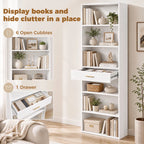 White tall bookcase with open cubbies and a drawer, styled with books