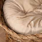 Beige soft cushion with tufted seams inside brown wicker cat bed basket