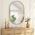 Gold-tone oval wall mirror with thin raised frame and centered round glass