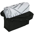 Rolled grey-and-white leaf-pattern outdoor rug inside black carry bag